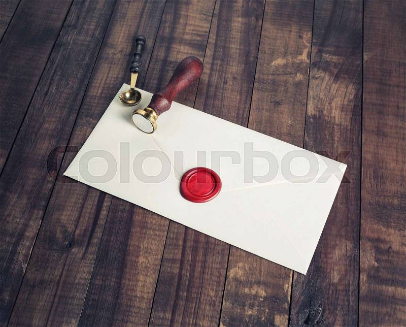 Old letter envelope with red wax seal and stamp on wooden background, stock photo