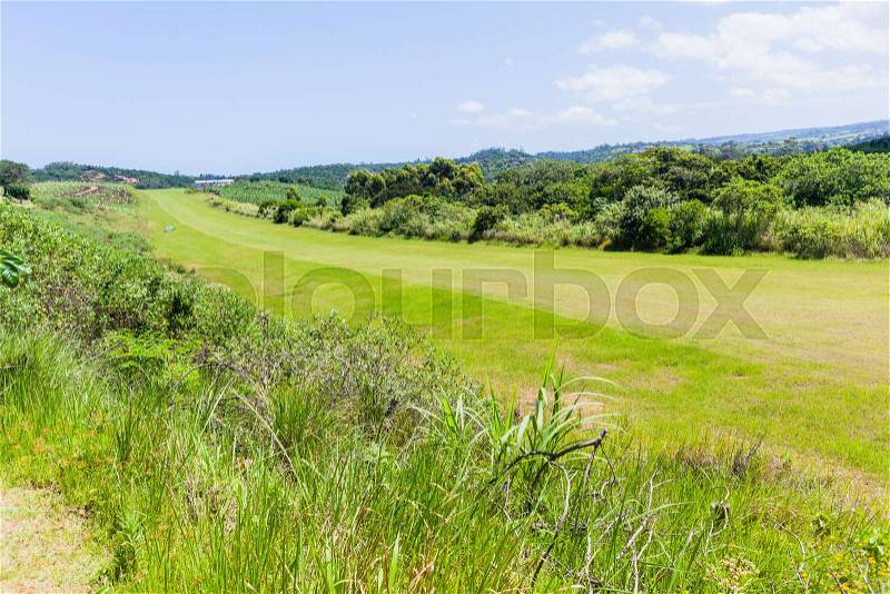 Airfield grass airstrip runway in countryside for light planes among farmland landscape, stock photo