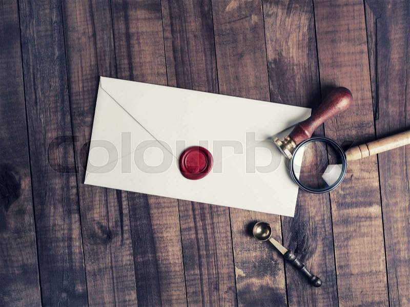 Old envelope with red wax seal, magnifier and stamp on wood table background. Flat lay, stock photo