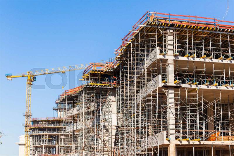 Construction building activity closeup scaffolding floor supports to concrete pouring high building in blue sky, stock photo