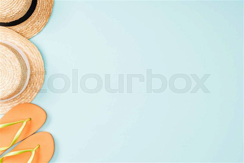 Top view of straw hats and flip flops on blue background, stock photo