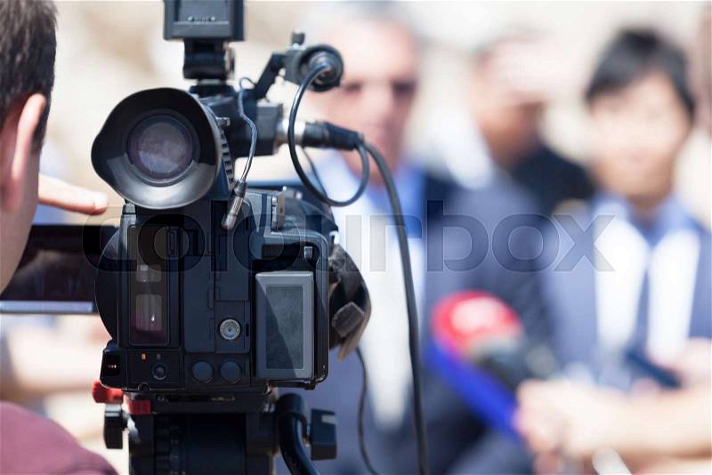 Covering news conference with video camera, recording public figure\'s statement for the media, stock photo