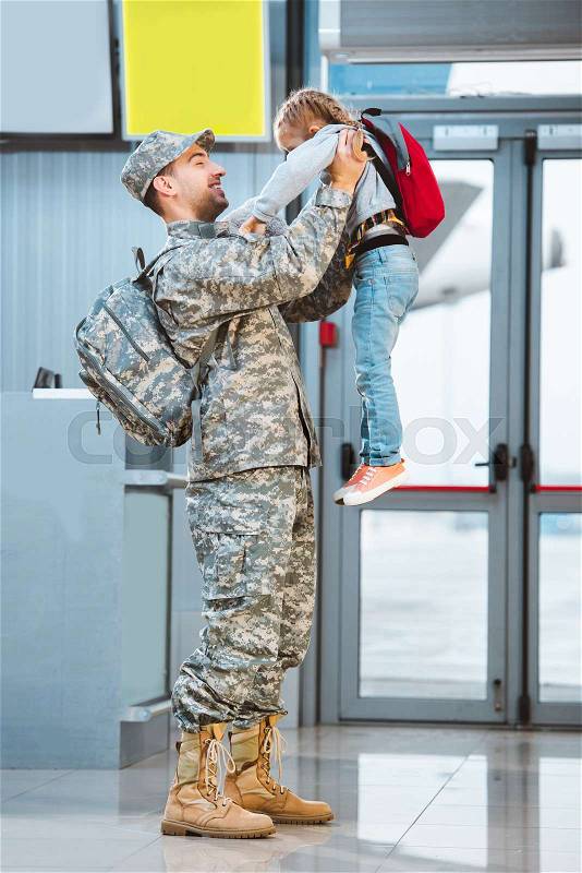 Happy father in military uniform holding in arms cute daughter in airport , stock photo