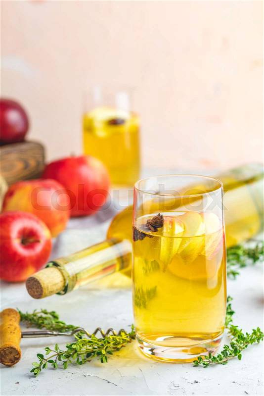 Bottle and glasses of homemade organic apple cider with fresh apples in box, light concrete table surface. Shallow depth of the field, stock photo