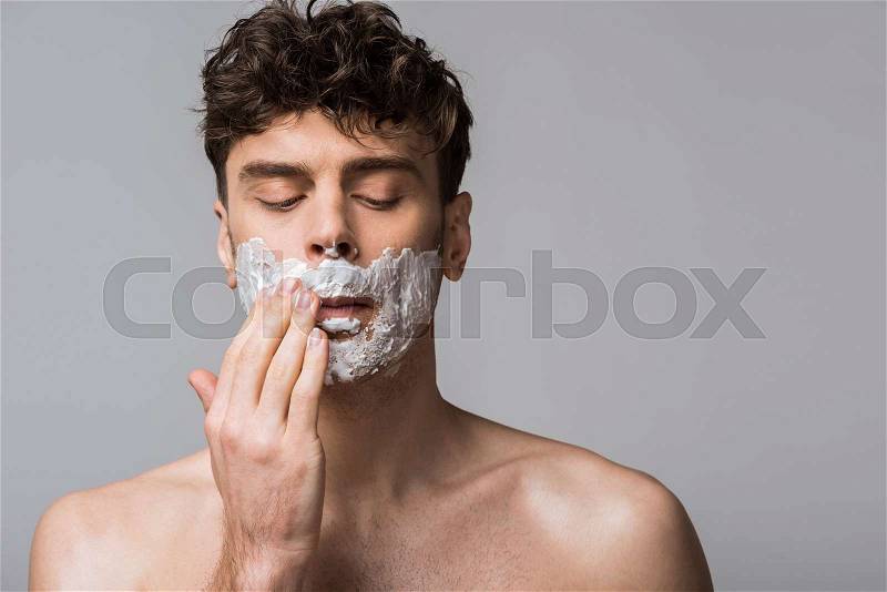 Handsome man applying shaving foam on face, isolated on grey, stock photo