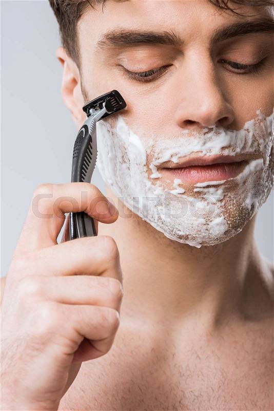 Close up of man foam on face shaving with razor, isolated on grey, stock photo