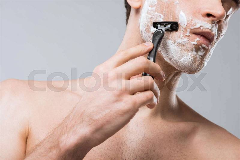 Cropped view of man foam on face shaving with razor, isolated on grey, stock photo