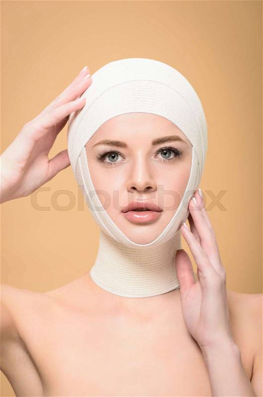 Naked young woman touching bandages over head and looking at camera isolated on beige, stock photo