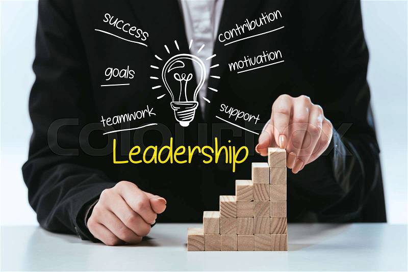 Cropped view of woman with wooden career ladder, components of leadership on foreground, stock photo