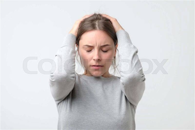 Young european stressed woman holding head in hands, stock photo