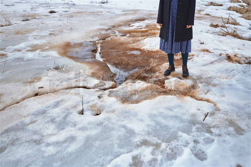 Woman standing at the puddle in winter landscape, stock photo