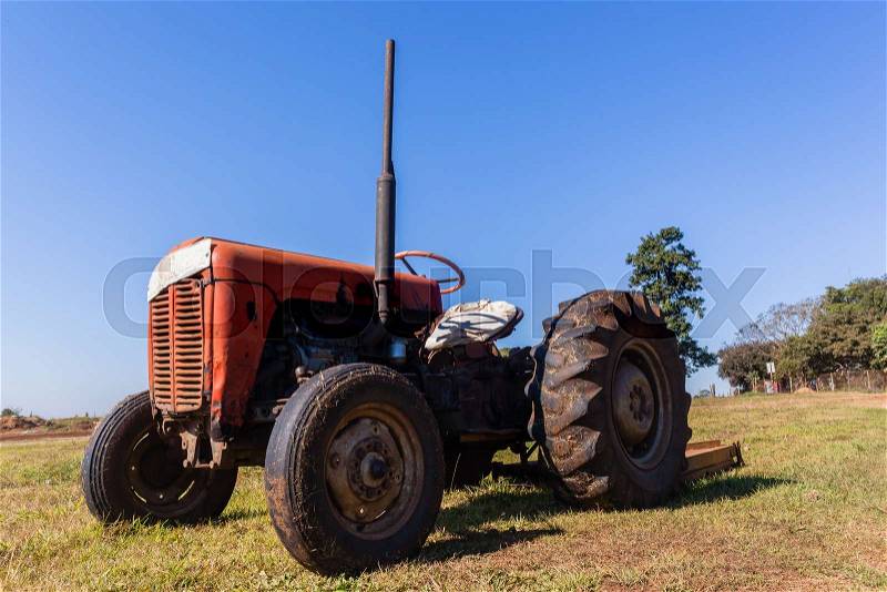 Old vintage tractor in field still operating with attached grass cutter, stock photo