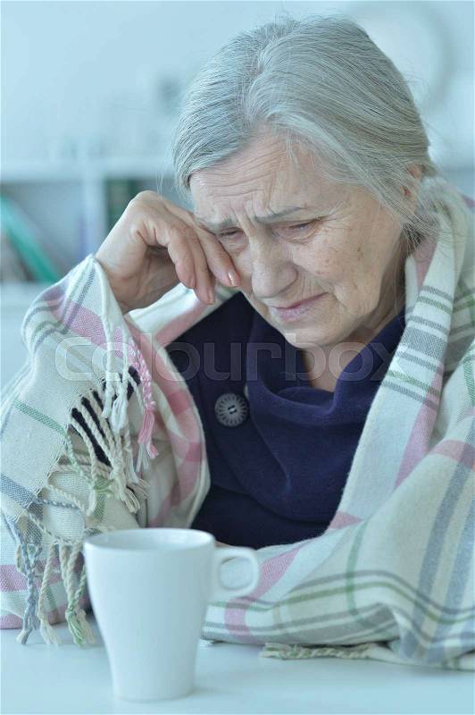Portrait of a sad old woman crying at home, stock photo
