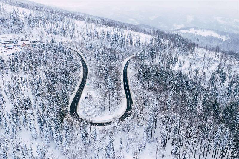 Curvy windy road in snow covered forest, top down aerial view. Winter landscape. , stock photo