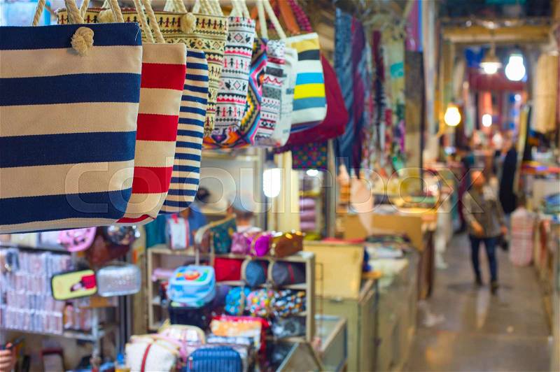 Grand Bazaar market in Tehran, rows of colorful textile crafts shops, bags in foreground, Iran, stock photo