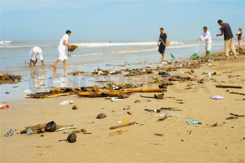 Group of people cleaning up beach from the garbage and plastic waste, stock photo
