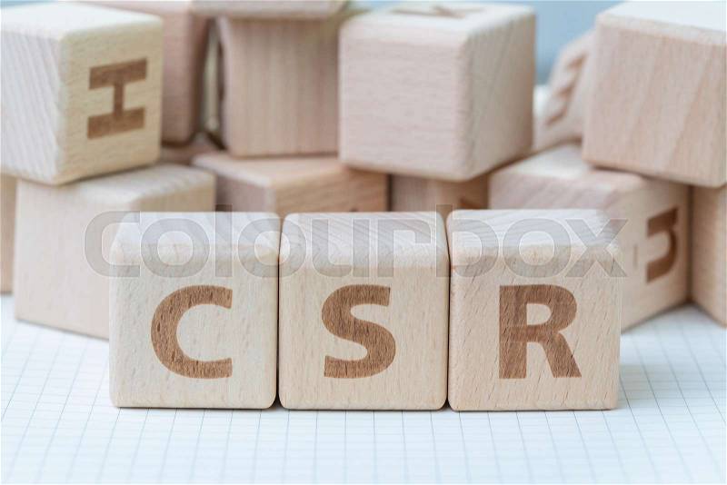CSR, Corporate Social Responsibility concept, wooden cube block with letters forming acronym CSR on white gridline notebook, activity that company help people and ..., stock photo