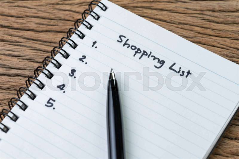 Shopping List, checklist to buy things from supermarket concept, pen with small notepad paper with handwriting headline as Shopping List and numbers on wood table, stock photo