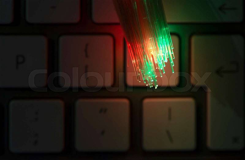 Colourful optic fibers illuminated on keyboard. High speed internet concept. Data transfer optic fiber cable. Bunch of many optical fibers, glowing different colors. ..., stock photo