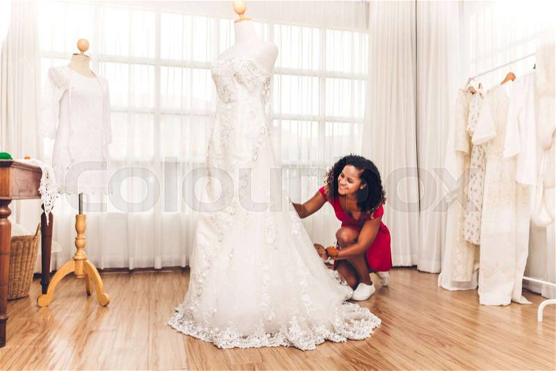 Smiling african american black woman fashion designer sit near mannequin and clothes at workshop studio, stock photo