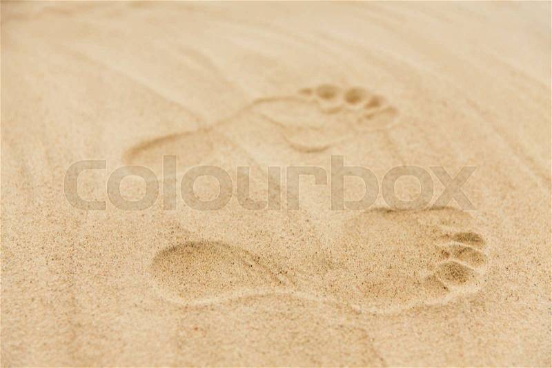 Summer vacation concept - footprints in sand on beach, stock photo
