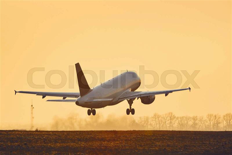 Airplane taking off from airport runway at sunset - copy space, stock photo