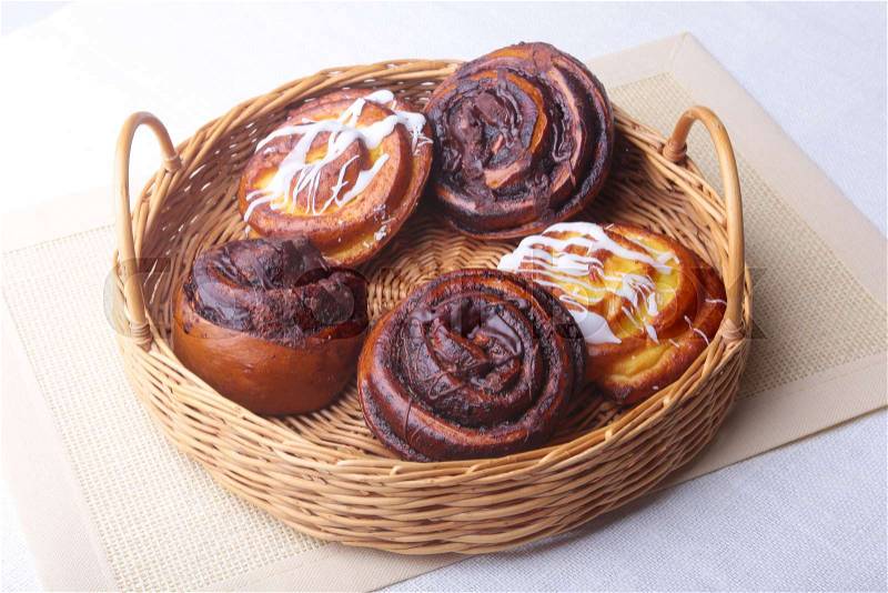 Freshly baked homemade sweet bun or sweet rolls with cinnamon in a wicker basket, stock photo