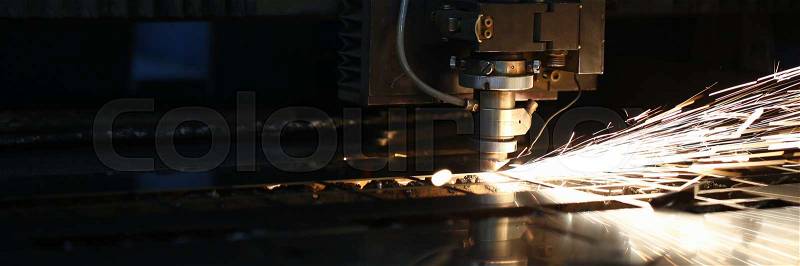 Sparks fly out machine head for metal processing laser metal on metallurgical plant background. Manufacturing finished parts for automotive production concept, stock photo
