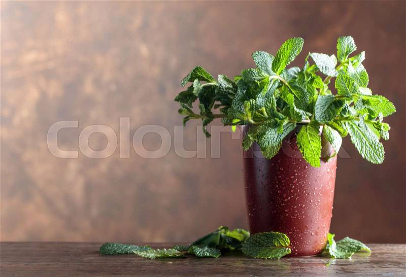 Bunch of fresh green organic mint on old wooden table. Brown background, copy space, stock photo