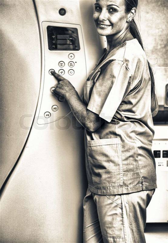 Smiling doctor setting up medical machine at hospital, stock photo