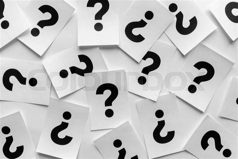 Bold black question marks on paper cards scattered randomly over a white background in a conceptual image, stock photo