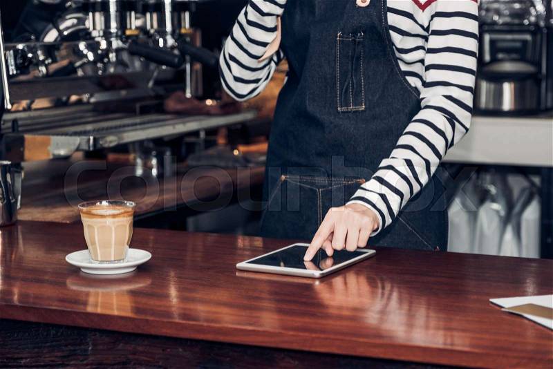 Woman barista take order by mobile and tablet,asia female waitress using digital device in coffee shop business at counter bar in cafe,modern food owner business ..., stock photo