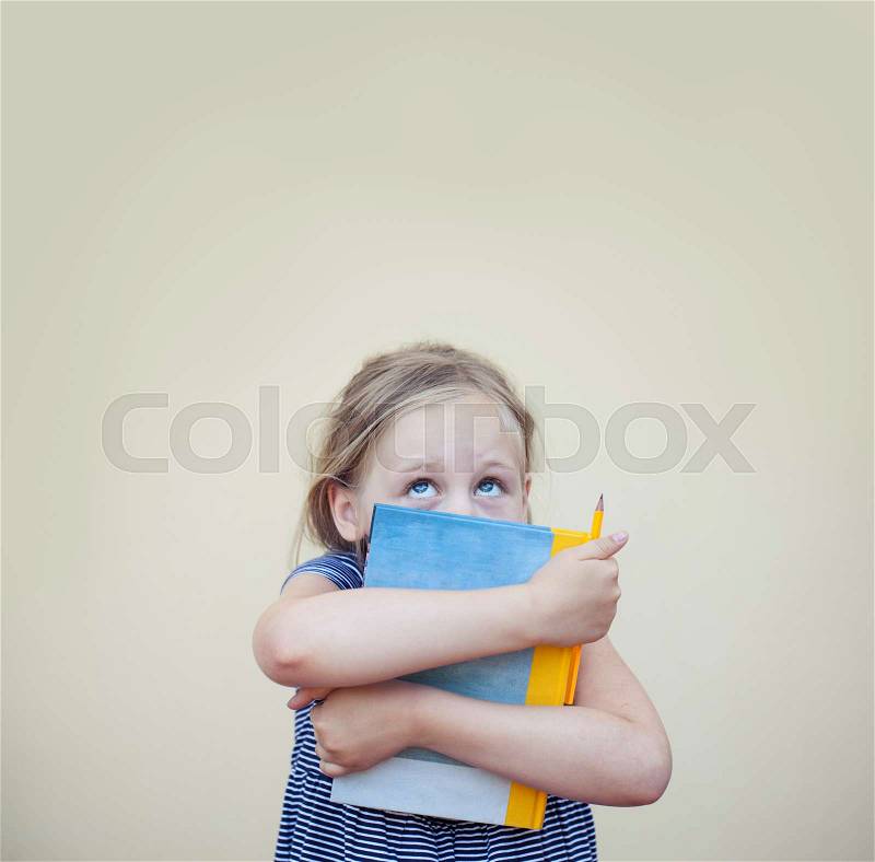 Funny child girl with book looking up on background with copy space, stock photo