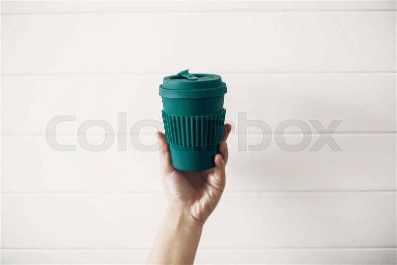 Hand holding stylish reusable eco coffee cup on white wooden background. Green Cup from natural bamboo fiber, zero waste concept. Ban single use plastic. Make a ..., stock photo