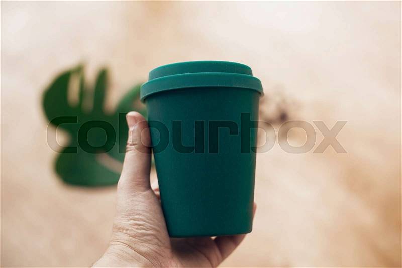 Ban single use plastic. Hand holding eco reusable coffee cup on wooden background. Coffee cup from bamboo fiber, zero waste concept. Take away coffee in your cup. ..., stock photo