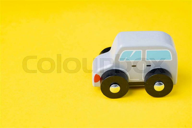 Cute wooden small toy car parking on vivid yellow background, car leasing, rental or insurance or automobile market concept, stock photo