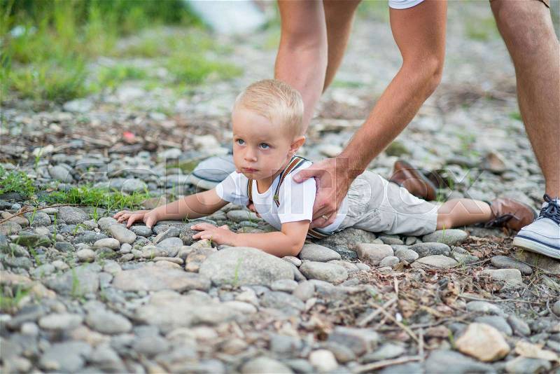 Unrecognizable father lifting a small toddler son from the ground in sunny summer nature, stock photo
