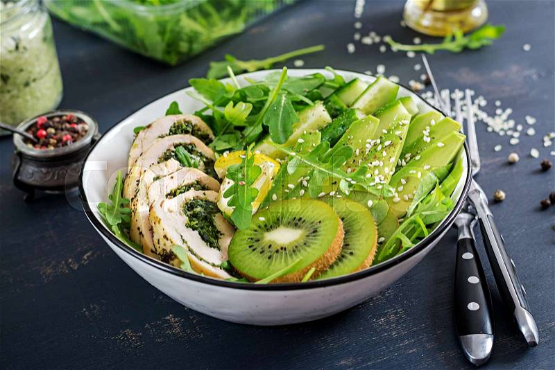 Buddha bowl dish with chicken fillet, avocado, cucumber, fresh arugula salad and sesame. Detox and healthy keto diet bowl concept. Overhead, stock photo