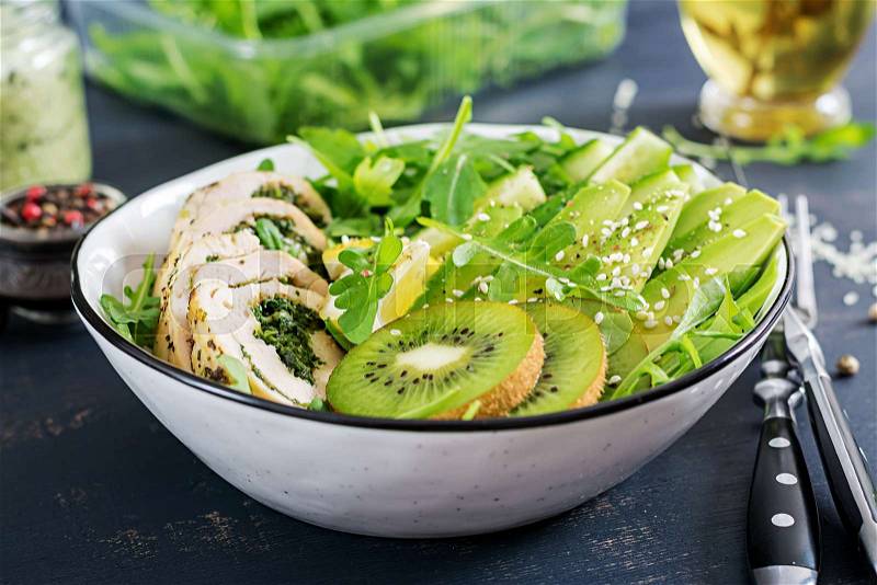 Buddha bowl dish with chicken fillet, avocado, cucumber, fresh arugula salad and sesame. Detox and healthy keto diet bowl concept. Overhead, stock photo