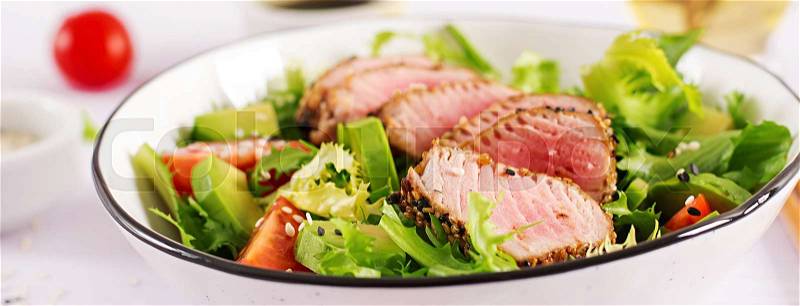 Tuna salad. Japanese traditional salad with pieces of medium-rare grilled Ahi tuna and sesame with fresh vegetable on a bowl. Authentic Japanese food. Banner, stock photo