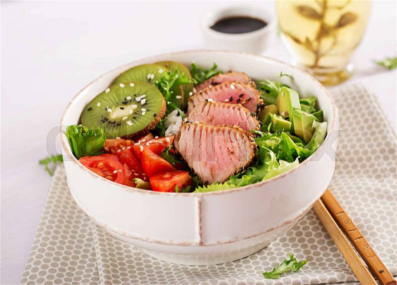 Salad. Poke bowl. Buddha bowl. Traditional salad with pieces of medium-rare grilled Ahi tuna and sesame with fresh vegetables and rice on a plate. Top view. Flat ..., stock photo