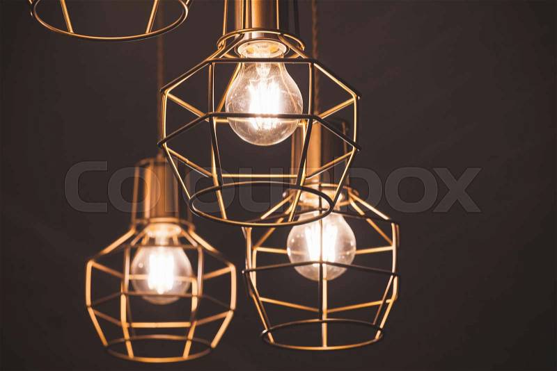 Chandelier with hanging bulb lamps, yellow LED lighting elements covered with metal wire frame lampshades, selective focus, stock photo