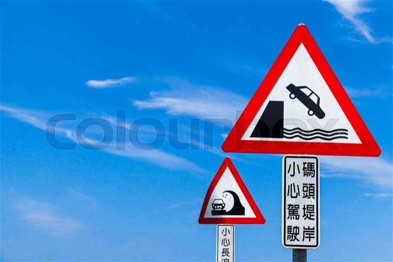 Caution Chinese road signs under blue sky. Text label means: Drive carefully, pier embankment, stock photo