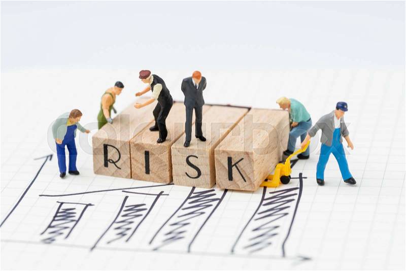 Risk assessment for business or investment, miniature figure businessman and company team standing on wooden stamp combine the word RISK and some worker try to move ..., stock photo