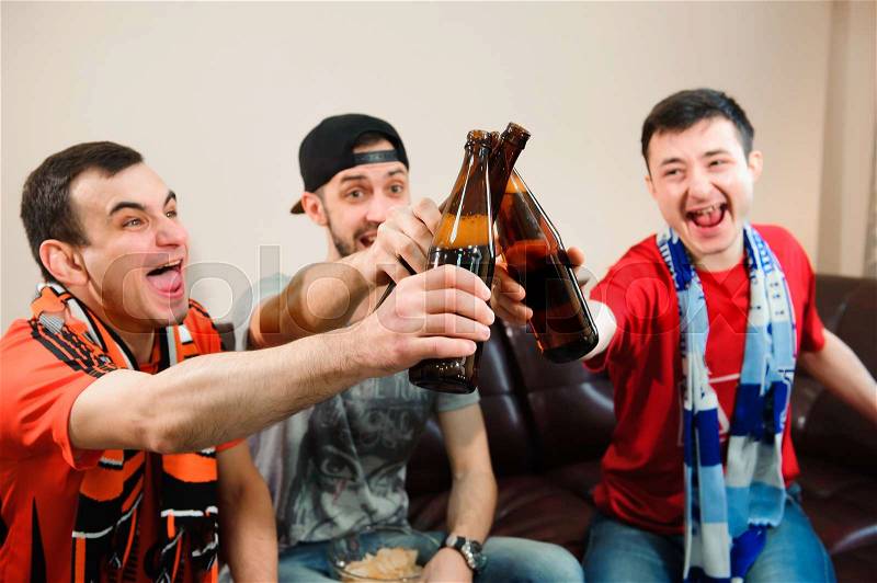 Young men drink beer, eat chips and root for football, stock photo