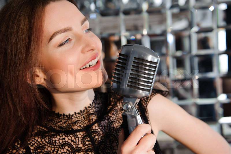 Rock star. Sexy Girl singing in retro microphone, stock photo