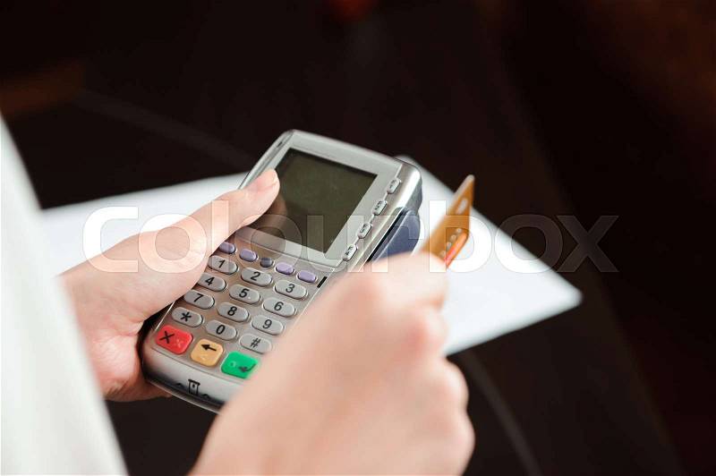 Hand swiping debit card on pos terminal, stock photo