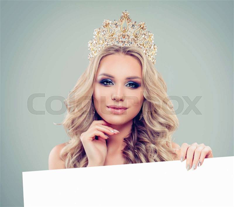 Happy glamorous woman in gold crown with white empty paper board background. Happy girl portrait, stock photo