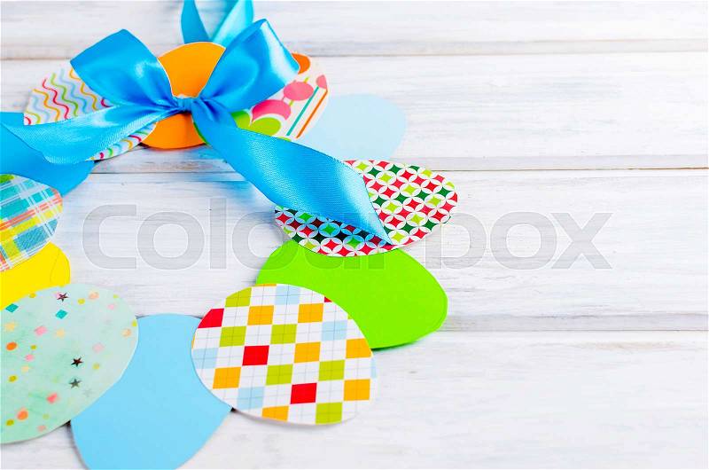 Craft of paper in the form of a wreath of colorful paper eggs on white wooden table. Child does crafts from paper. Idea project for kindergarten, Kids crafts. How ..., stock photo