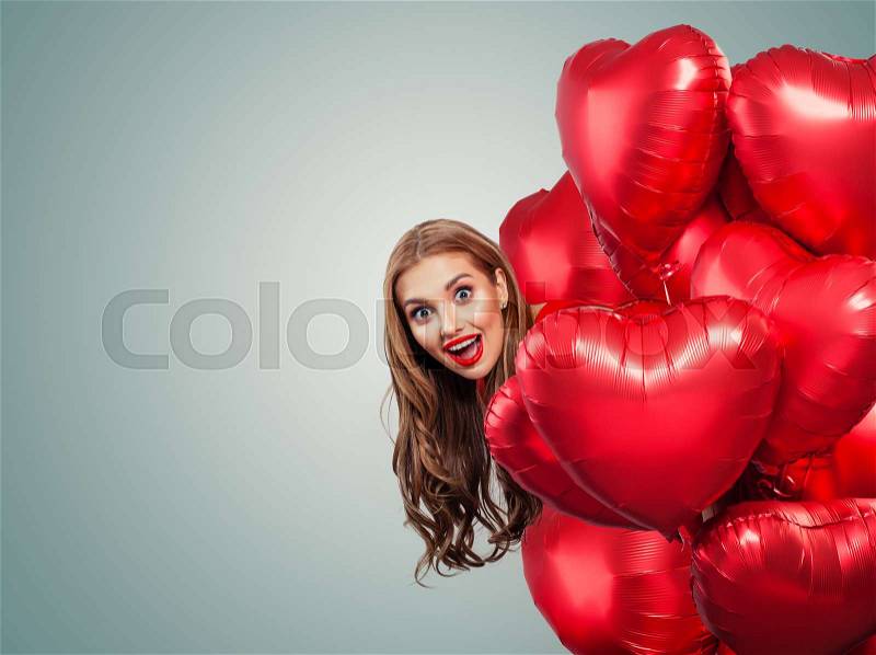Happy surprised woman withred balloons. Perfect smiling girl with red lips makeup portrait. Surprise, valentines people and Valentine\'s day banner background with ..., stock photo
